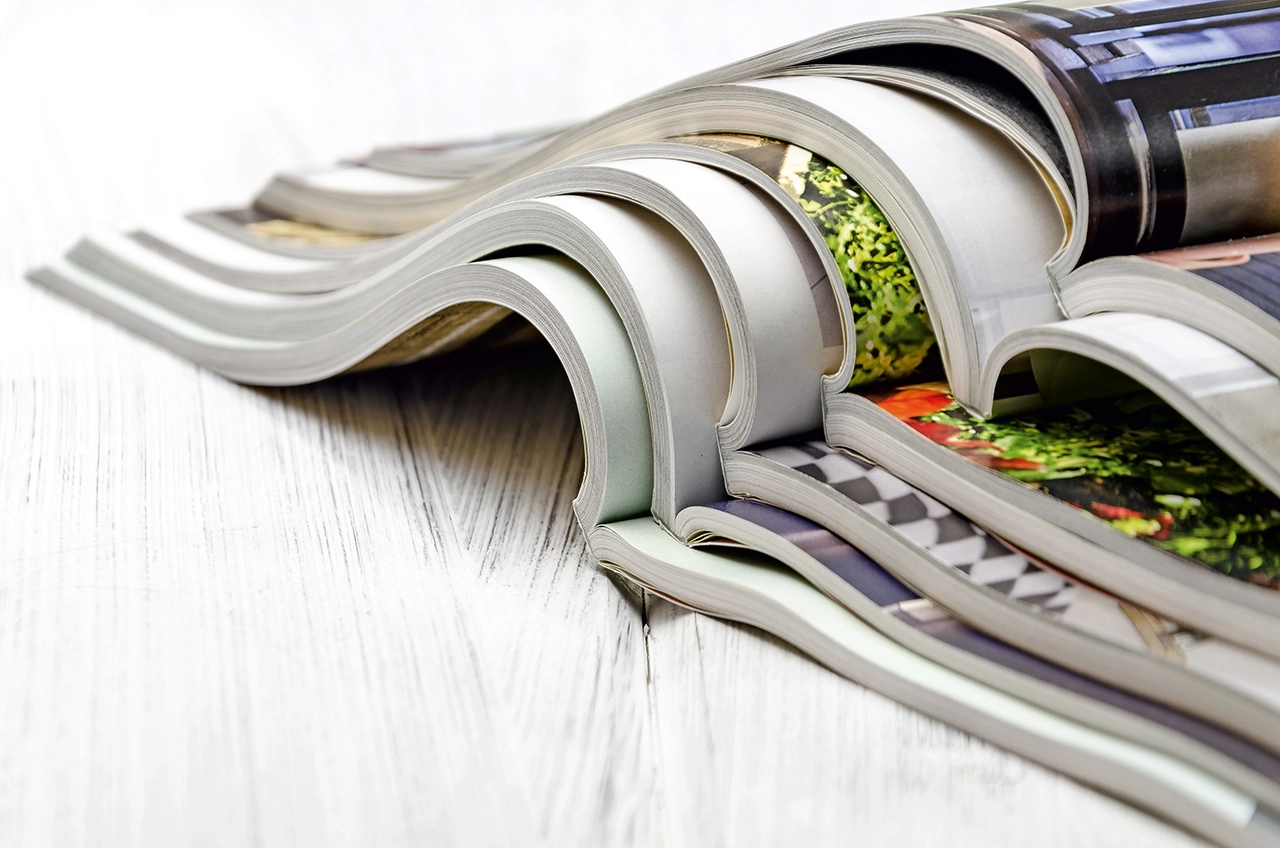 stack of magazines on a white wooden background