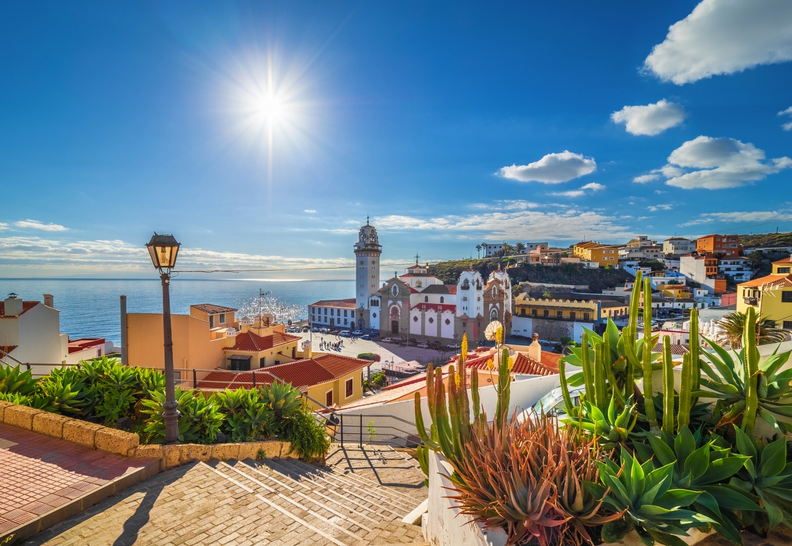 Treppen führen zu einer Kirche in einem sonnigen Küstendorf mit Blick aufs Meer.