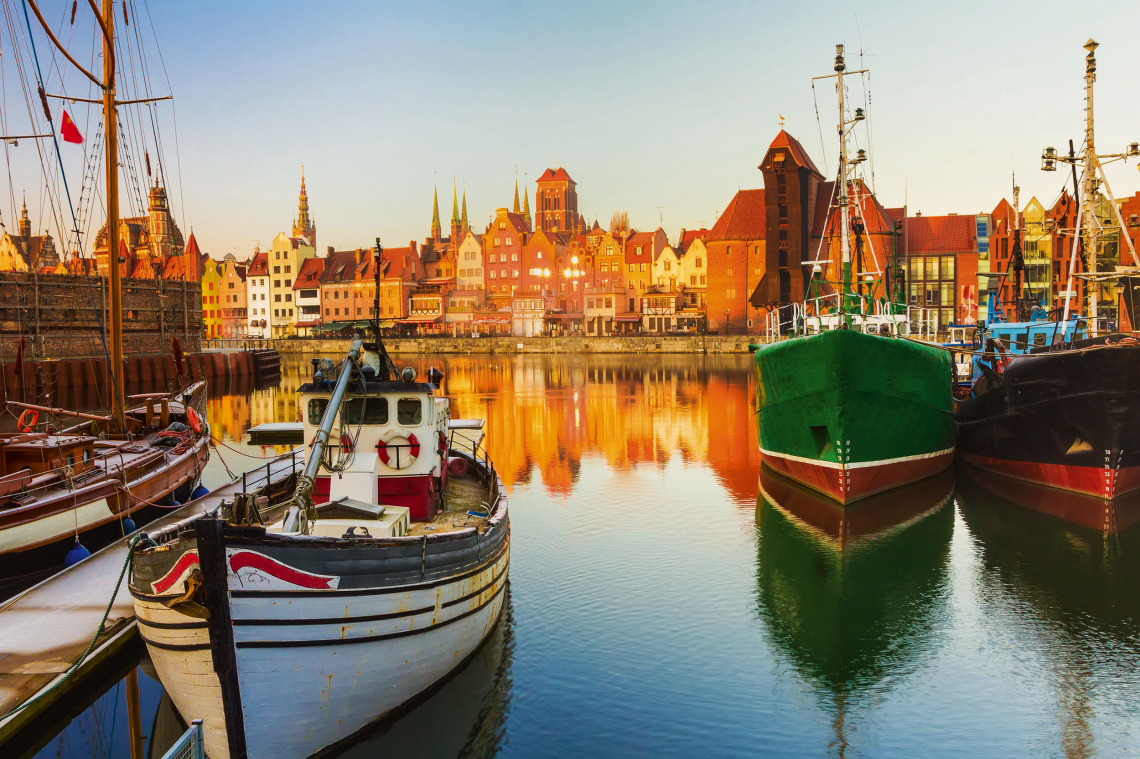 Boote im Hafen vor historischer Altstadt bei Sonnenuntergang.